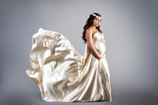 Femme enceinte dans une robe en satin beige