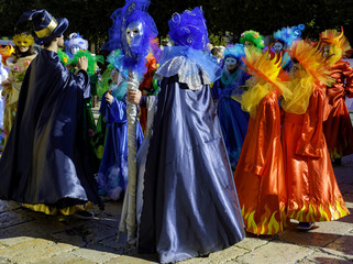 Fototapeta premium Young people and children with beautiful and colorful clothes during the parade of masked groups in the city streets of a city in Puglia. Italy