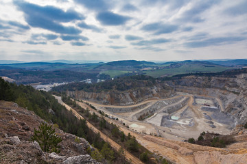 Fototapeta na wymiar Surface mine in czech republic with forests and hills behind.