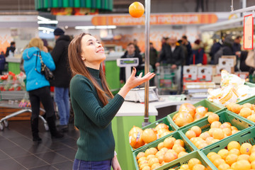 young woman in a store throws an orange