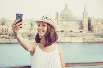 Young woman tourist taking selfie on mobile phone, Valletta - Malta  cityscape