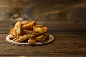 Grilled potatoes on a cork stand on a dark wooden background