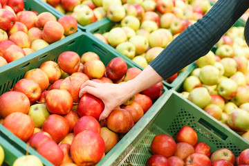Close up view of woman hand selecting apple in supermarket