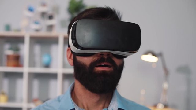 Portrait young man wearing virtual reality glasses sit on the sofa home feel shock innovation looking modern entertainment gadget close up face new tech visual beard game hipster slow motion