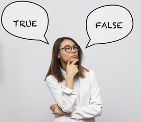 Young pretty asian woman thinking about choice between saying false or true. Businesswoman choosing concept. Selective focus and shallow DOF
