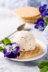Fototapeta na wymiar Vanilla ice cream scoop with edible flowers pansy. Summer food concept.