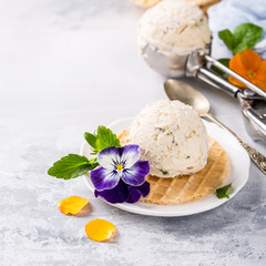 Vanilla ice cream scoop with edible flowers pansy. Summer food concept with copy space.