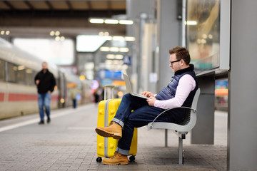 Freelancer working with a laptop in a train station while is waiting for transport