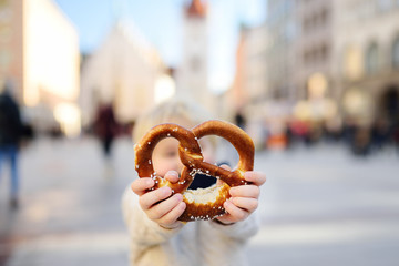 Little tourist holding traditional bavarian pretzel in Munich