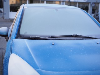 Blaues Auto mit vereister Frontscheibe