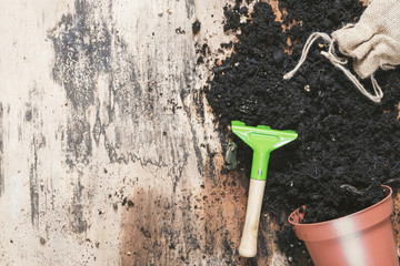 Small rake and flower pot with soil - Spring gardening theme image with an overturned flower pot...