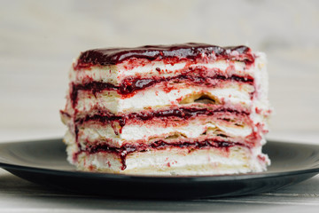 Piece of cake Napoleon with  blueberry jam on black plate