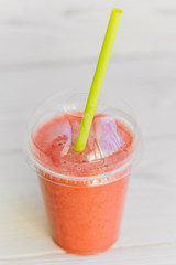 strawberry smoothie in plastic glass 2go with cocktail tube. Healthy apple banana and strawberry blended drink to go.