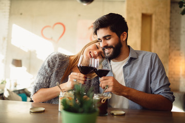 Young attractive couple drinking red wine. Couple celebrating anniversary, Valentine's day or International woman's day.