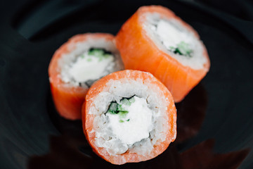 Roll philadelphia made of fresh salmon and cream cheese inside on black plate. Asian traditional food