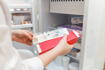 The doctor takes out medicine from the refrigerator with a disposable syringe