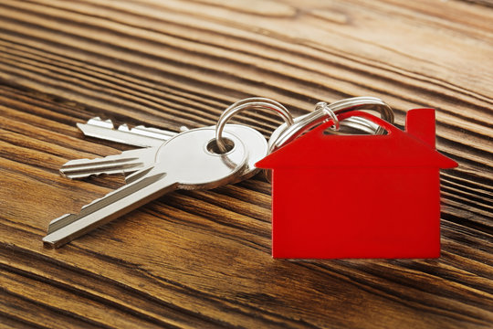 Real estate concept, red keychain with house symbol wooden backgtound