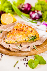 Pie with salmon, potato and spinach on wooden cutting board