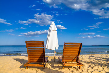 Coastal landscape - Beach umbrellas and loungers on the sandy seashore, the Kavatsi bay near city of Sozopol in Bulgaria