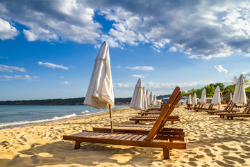 Coastal landscape - Beach umbrellas and loungers on the sandy seashore, the Kavatsi bay near city of Sozopol in Bulgaria