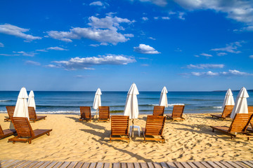 Coastal landscape - Beach umbrellas and loungers on the sandy seashore, the Kavatsi bay near city...