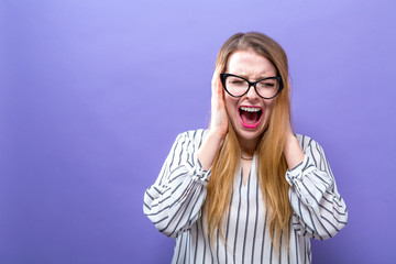 Young woman blocking her ears on a solid background