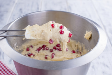 Red berries in a dough for a home-made pie. In a steel bowl. White wooden background and free space for text.