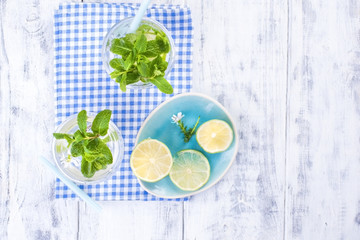 Two glasses of water and fresh green mint, and lime. On a blue napkin on a wooden background. free space for text or a postcard.