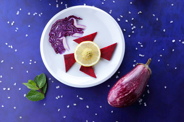 Violet cabbage and mint, onions and red beets on a white plate, lemon, eggplant on an ultraviolet background, large salt, purple onion, cabbage on a dark blue background, pop art