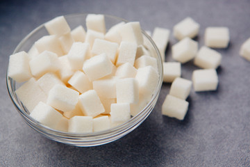 Fototapeta na wymiar White sugar cubes in bowl on gray background