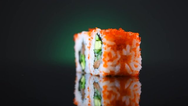 Sushi rolls rotated over black background. Sushi roll set with tuna, vegetables and flying fish roe closeup. 4K UHD video footage. 3840X2160