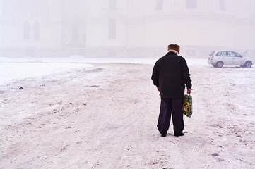 an old man walking along near the Ascension Cathedral in Novocherkassk on a foggy winter day