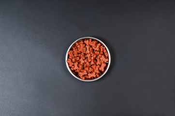 Dry dog pet food in bowl on blach chalkboard background top view. Pet feeding concept backgrounds with copy space. Photograph taken from above.