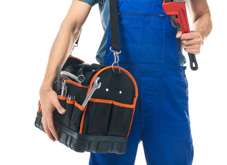 Young plumber in uniform with tool bag and pipe wrench on white background