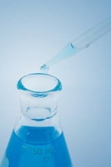 laboratory glassware with water and empty with reflection isolated on blue background