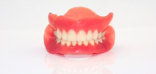 Zwei zusammengeh&ouml;rende zahnmedizinische Totalprothesen so aufeinandergelegt, dass sie ein L&auml;cheln bilden