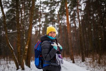 Fototapeta na wymiar Side view of girl with backpack in winter forest