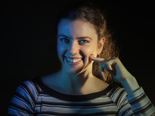 Portrait of a white woman on black background, gesture finger to cheek, Italian gesture delicious....