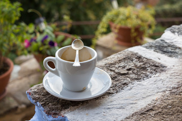 A white cup of espresso coffee on a stone.