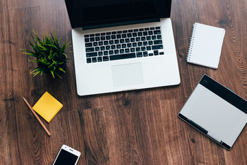 on a wooden table is a laptop, phone, notebook
