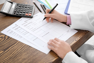 Doctor filling in insurance form at table