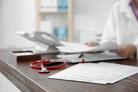 Insurance forms with stethoscope and doctor on background