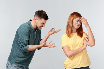 Emotional couple during quarrel on light background