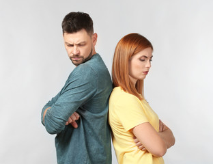 Angry couple after quarrel on light background