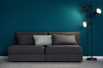 Elegant living room interior with comfortable sofa near wall