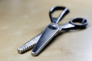 Garment accessories spread on a light wooden table. Threads, scissors and sewing needles in a tailoring workshop.