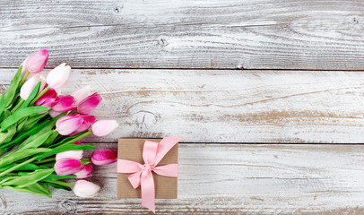 springtime pink tulips and gift box on white rustic wooden boards