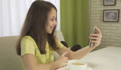 Teenage girl talks on skype during breakfast