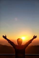 Fototapeta premium Happy Businessman show hand up for successful at beautiful sunset time, Silhouette the man hand at sunset,Silhouette of Man Raising His Hands or Open arms when sunset..