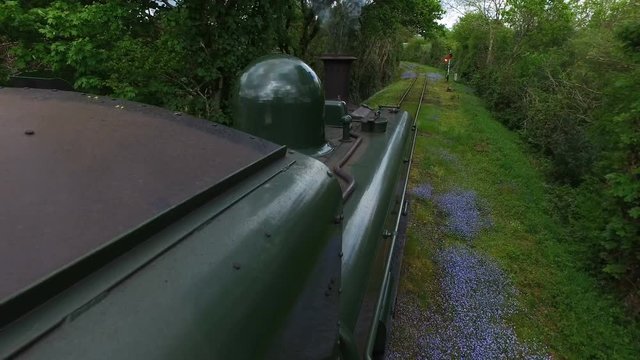 Devon, United Kingdom. 20th of July 2016. High right side mounted view of a Great Western Railway steam train passing through woodland.